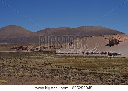 Eroded cliffs along the wide valley of a tributary of the River Lauca high on the Altiplano of northern Chile in Lauca National Park.