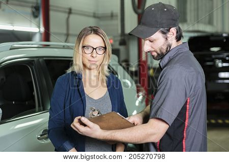 An auto mechanic and female customer in garage