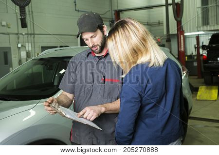 An auto mechanic and female customer in garage
