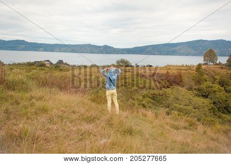 woman standing on hill looking at the lake toba