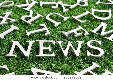 Wood alphabet wording news on artificial green grass background