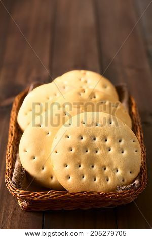Traditional Chilean Hallulla bread rolls in basket photographed on dark wood with natural light (Selective Focus Focus on the first roll)