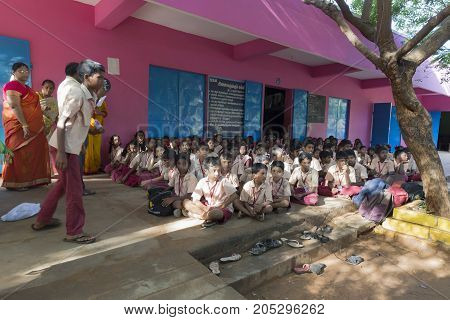 PONDICHERY PUDUCHERY INDIA - SEPTEMBER 04 2017. Outdoor meeting of the children of the school with uniforms sitting on the floor waiting for sport equipments as a gift from an association.