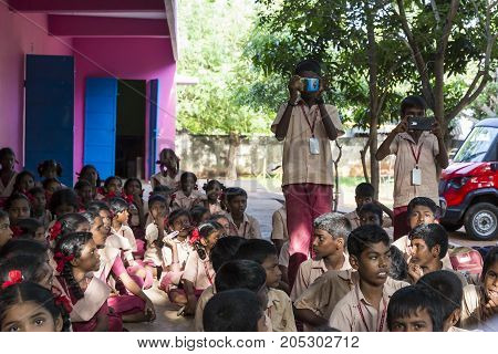 PONDICHERY PUDUCHERY INDIA - SEPTEMBER 04 2017. Outdoor meeting of the children of the school with uniforms sitting on the floor waiting for sport equipments as a gift from an association.