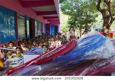 PONDICHERY PUDUCHERY INDIA - SEPTEMBER 04 2017. Outdoor meeting of the children of the school with uniforms sitting on the floor waiting for sport equipments as a gift from an association.