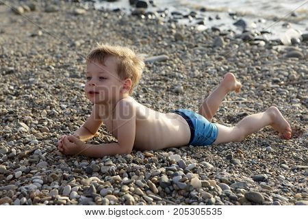 Сhild lying on pebble beach of the Sea of Azov