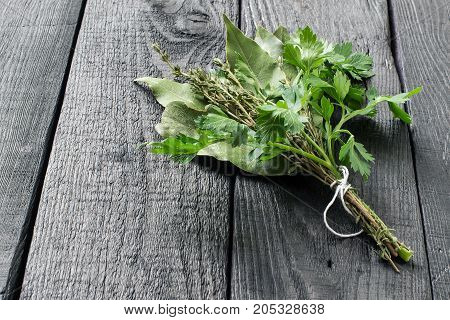 Bouquet garni. Classical french composition. Bay leaf parsley and thyme bound with culinary thread. Bunch of fresh aromatic herbs on dark wooden table