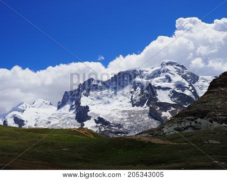 Monte Rosa massif, landscape of alpine mountains range in swiss Alps at SWITZERLAND seen from Gornergrat near Zermatt village, cloudy blue sky in 2017 warm sunny summer day, Europe on July
