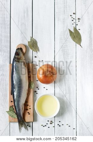 Herring with onions, vegetable oil and spices on a wooden board. The background. Rustic style, selective focus.
