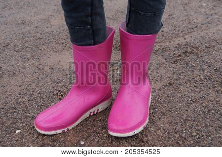 Girl standing in pink rubber Dunlop child rain boots.