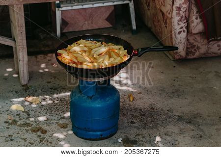Fried potatoes in a frying pan in the yard on a gas burner