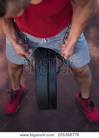 A hot, sexy young man with muscular body training outdoors. Handsome sportsman exercising in gym.
