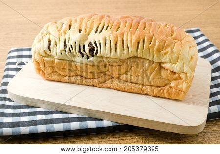 Cuisine and Food A Homemade Loaf of Brown Raisin Bread on Wooden Cutting Board.