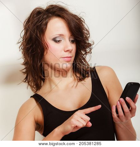 Sexy lazy girl in body underwear sitting on bed texting on mobile phone. Woman relaxing lazing in bedroom at the morning.