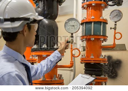 Engineer checking Condenser Water pump and pressure gauge chiller water pump with pressure gauge.