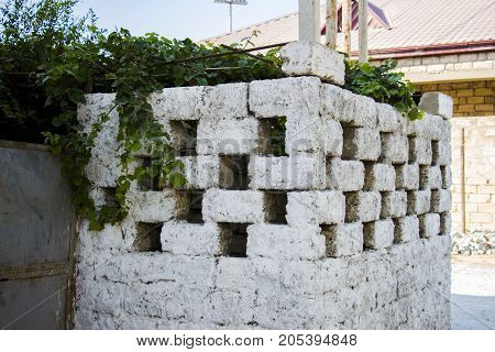 A fence made of white cubes covered with green branches