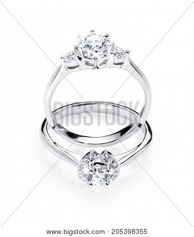 two diamond engagement wedding rings on isolated white background with light reflection one ring standing up one ring laying down