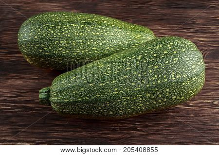 Raw Freshly picked organic marrow zucchini vegetables with leaves on wooden table.