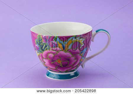 Beautiful stylized empty rose tea cup isolated on lilac background