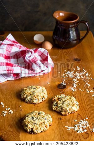 Vertical shot of oats cookies on rustic wooden table with egg shells cloth and jug - Homemade biscuit background
