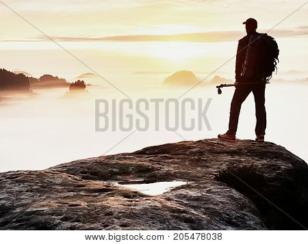 Man Silhouette With Poles In Hand. Sunny Spring Daybreak And Tourist Guide Stay On Sharp Cliff Of Mo