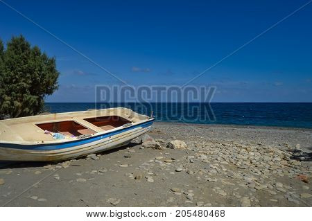 View of the pebble beach of Maleme with a boat abandon in the north west of the island of Crete in Greece