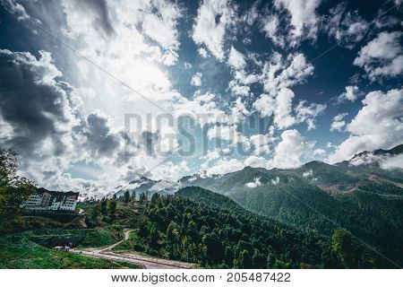 Stunning wide-angle shooting of mountain ridge and resort Rosa Khutor with one of its hotel and several ropeways in different distances; 