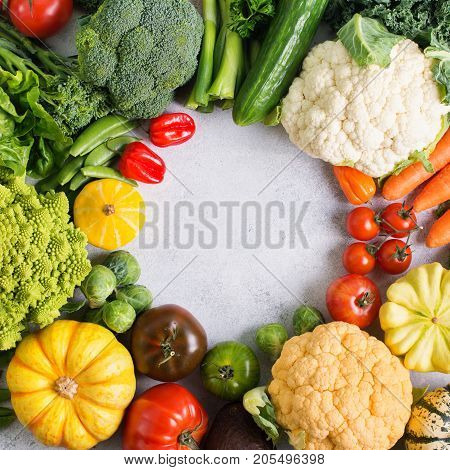 Above view of colorful vegetables arranged in a circle on the light grey background, copy space for text in the middle, selective focus