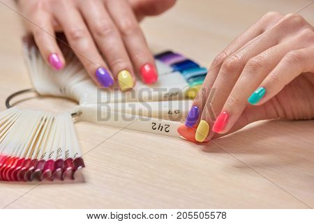 Female hand holding nails colors samples. Womans summer shellac nails. Choice summer fashion manicure.