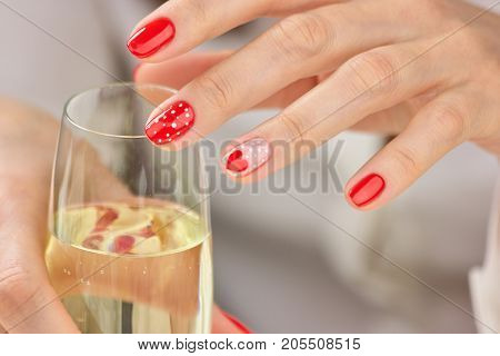 Female manicured hands and champagne. Young woman hands with beautiful polished nails holding glass of champagne. Romance and celebration concept.