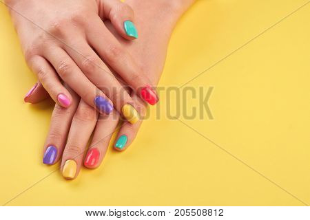 Female hands with summer manicure. Teen girl hands with bright summer manicure on yellow background, copy space.