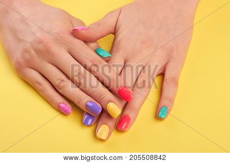 Woman nails painted in different colors. Stylish colorful nails and on a bright background. Nail care studio.