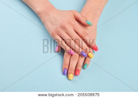 Female beautiful manicured hands. Woman hands with stylish colorful nails on light blue background. Skin and nail care.