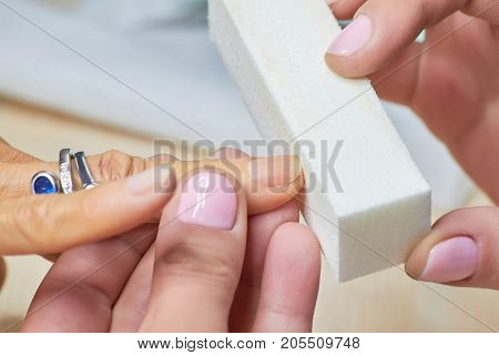 Manicure nail buffering close up. Manicure process in a beauty salon, nail beautician using nail buffer.