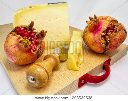 wood chopping board with assortment of cheeses and pomegranate fruit. for food concept