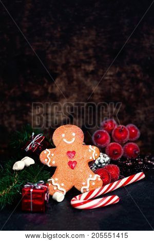 Christmas composition with Christmas gift Gingerman cookie fir tree branches xmas holiday decorations and festive symbols on dark background with copy space for your design or Happy New Year text
