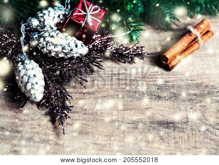 Christmas Card with Christmas gifts fir tree branches xmas holiday decorations festive symbols and falling snow on bright wooden background with copyspace