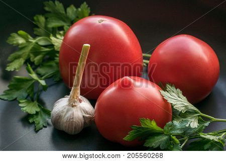 Tomatoes with garlic and parsley on dark background