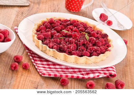 Raspberry tart with fresh rasperries in white bowl.