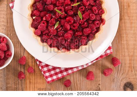 Raspberry tart with fresh rasperries in white bowl.