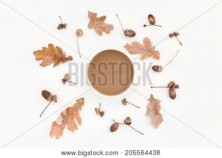 Round autumn pale pattern leaves acorns and cup of coffee on white background