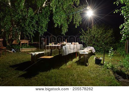 A table in the courtyard at night after a banquet in the light of a street lamp.