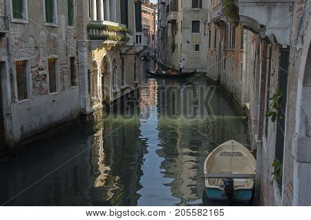 Venice, Italy - September 23, 2011: Traditional gondola ride in small canal at residential district of historical buildings and bridge, Venezia, Venice, Italy, Europe . Visit in place.