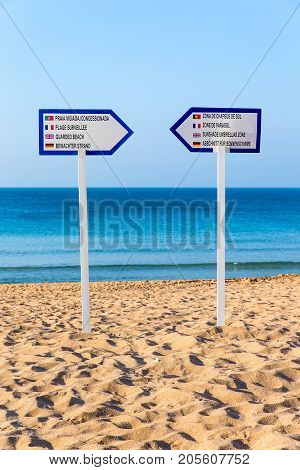 Two information signs stand on sandy beach at sea