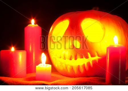 Jack O' Lantern and candles on a table on a dark background. Pumpkin carved for Halloween