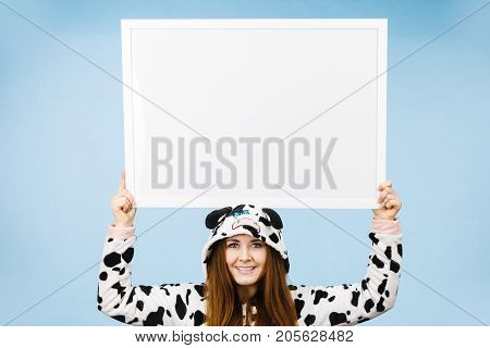 Smiling teenage girl in funny nightclothes pajamas cartoon style with blank empty banner board. Advertisement copyspace.