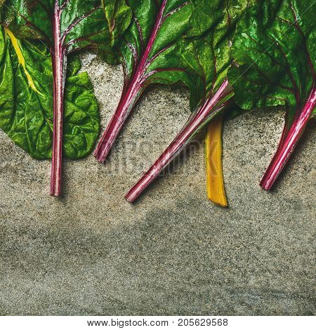 Flat-lay of fresh leaves of swiss chard over concrete stone background, copy space, top view, square crop. Food frame. Clean eating, vegan, vegetarian, alcaline diet, organic, healthy cooking concept