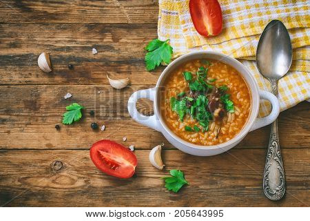 kharcho soup from rice beef tomatoes spicy herbs in white bowl on an old wooden table traditional Georgian cuisine top view