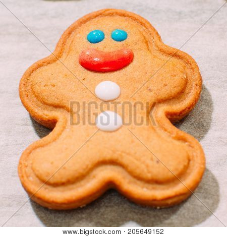 Homemade Christmas bakery close up. Festive background of smiling gingerbread man on cooking sheet. Family celebration and New Year traditions concept