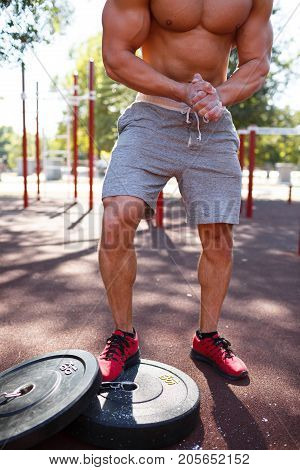 Sporty and healthy muscular man exercising outdoors. Sexy young man with a muscular body on a natural background. Strong and perfect male body.